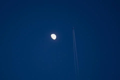 A moon is in the sky above a jet Stock-Fotos