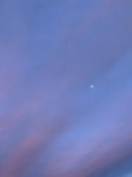 The moon is slightly visible through the clouds. Stock Photos