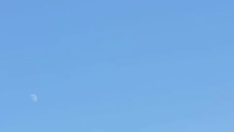 Moon at a two quarter phase against a blue early afternoon sky Stock Footage 165996796