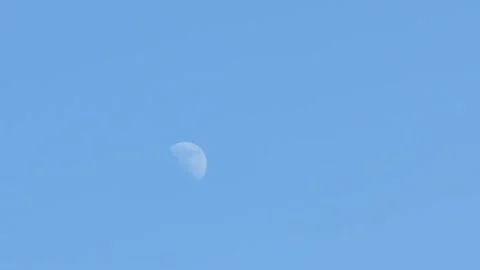 Moon at a two quarter phase against a blue early afternoon sky Stock Footage 165998736