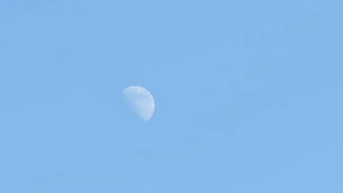 Moon at a two quarter phase against a blue early afternoon sky Stock Footage 165998945
