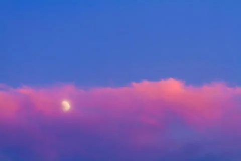 Moon under pink cloud on blue sky Stock Photos