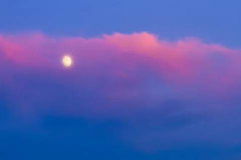 Moon under pink cloud on blue sky Stock Photos
