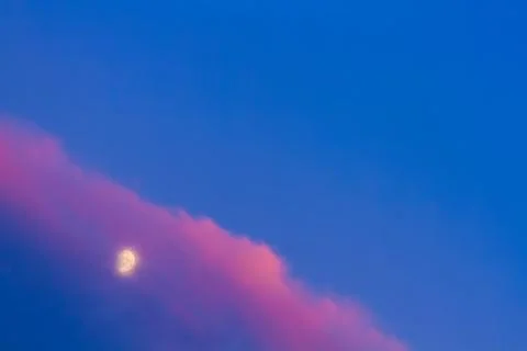 Moon under pink cloud on blue sky Stock Photos