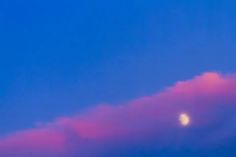 Moon under pink cloud on blue sky Stock Photos