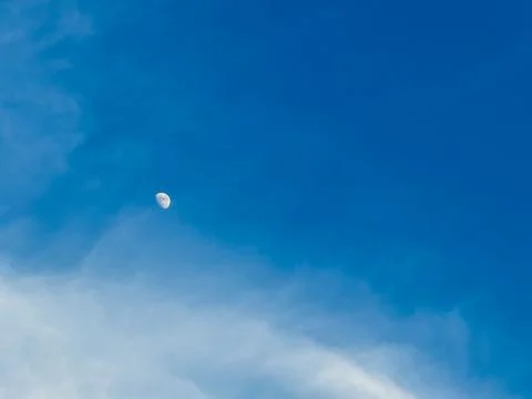 Moon visible in the blue sky during the day with few clouds Foto stock