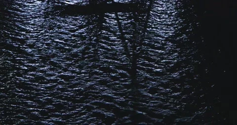 Moonlight Casting Light and Shadows on Ripples of Water at Night on Calm Stock Footage 242998696