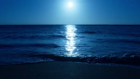 Moonlight reflecting over dark blue sea and soft waves sparkling at beach night Stock Footage