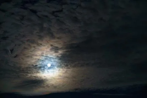 Moonlight shines through clouds at night Stock Photos