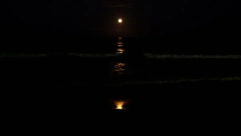 Moonlight stripe rippling over ocean surface as strawberry full moon rises Stock Footage 340922266