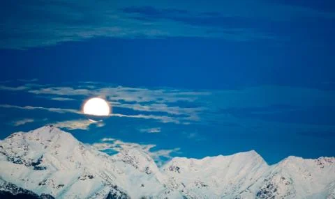 Moonset behind snowed mountain Stock Photos