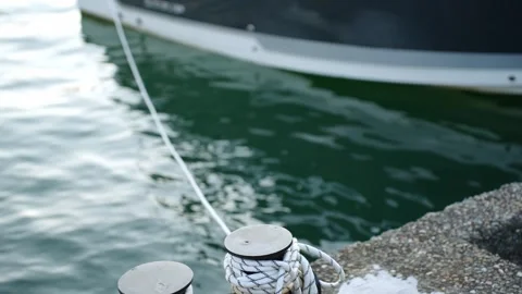 Mooring rope wrapped around cleat on concrete pier close up, boat moored in Vidéo 342824780