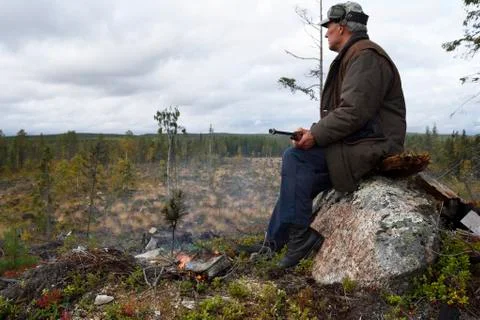Moosehunter sitting on a stone with a fire in front of him Stock Photos