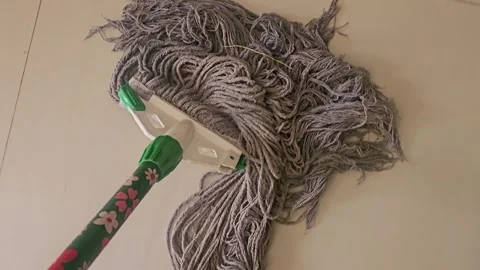 A mop with gray strings, a green handle, and a white head is shown Video stock 315423634