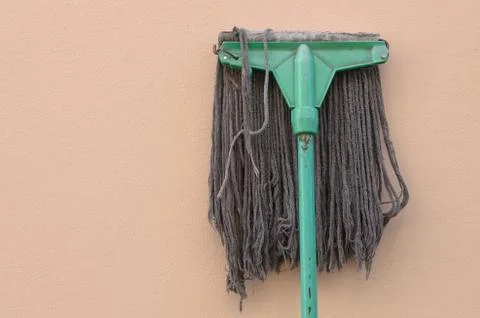 A mop lying against a wall. Stock Photos