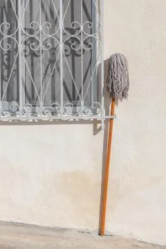 A mop stood outside a window of a house. Minimalist composition. 库存照片