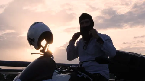The moped rider pulls a black balaclava over his head. Stock Footage 313197874