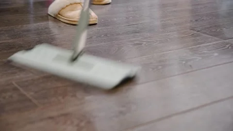 Mopping dark hardwood floor with microfiber mop and slippers visible Stock Footage 323178956