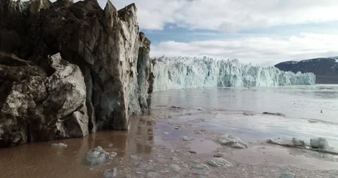 Moraine side of tidewater glacier front with birds flying around on Svalbard Stock Footage 147149139
