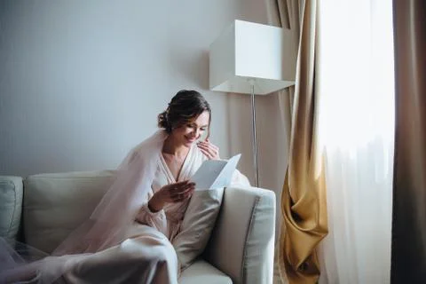 Morning bride, beautiful bride is waiting for the wedding sitting on the sofa in Stock Photos