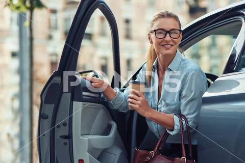 Morning with coffee. Fashionable smiling middle aged business woman holding Stock Photos