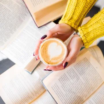 Morning coffee with a pattern on the background of books. Stock Photos
