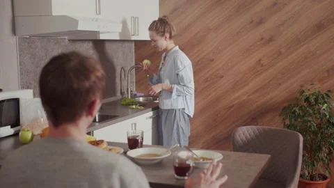 In the morning, in the kitchen, the guy has breakfast at the table, the girl Video stock 145065065