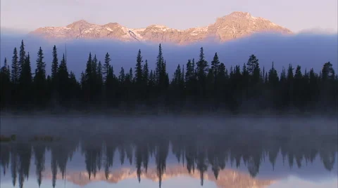 Morning light on mountain range with forest and misty lake Stock Footage 50520077