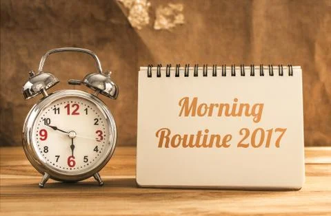 Morning routine 2017 text on notebook with alarm clock on wood table. Stock Photos