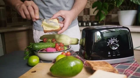 Morning routine man makes crispy toasts with avocado and vegetables for healthy Stock Footage 311865173