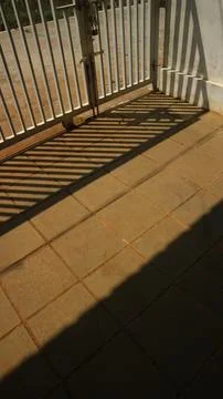 Morning sunlight creating geometric patterns on tiled ground with shadows f.. Stock Photos