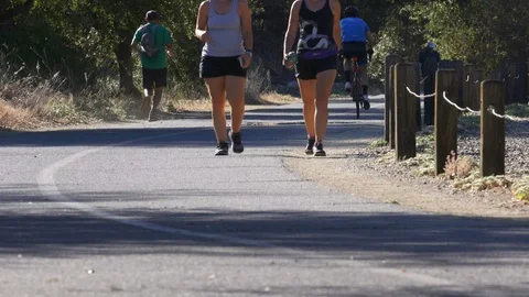 Morning walkers cyclists exercise paved trail Stock Footage 91751558