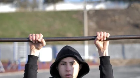 In the morning the young athlete makes pull ups at the sports ground Stock Footage 125803756