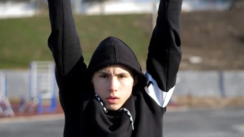 In the morning the young athlete makes pull ups at the sports ground Stock Footage 125803765