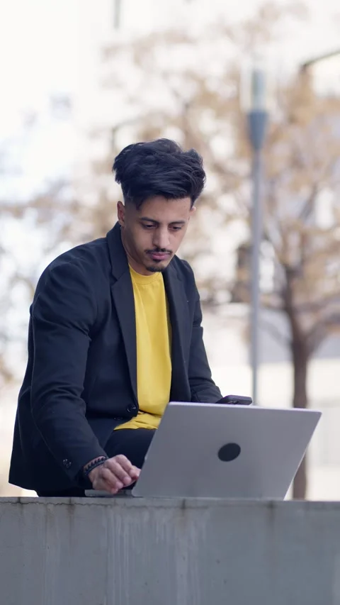 Moroccan freelancer working on a laptop computer outdoors. Vertical Stock Footage 340170753