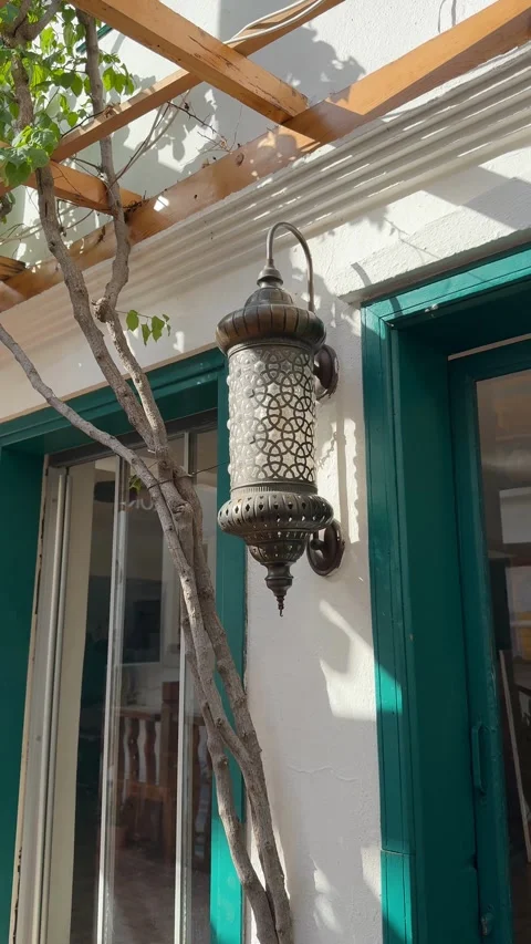 Moroccan lantern casting intricate shadows on white wall with green doors i.. Stock Footage 331385349