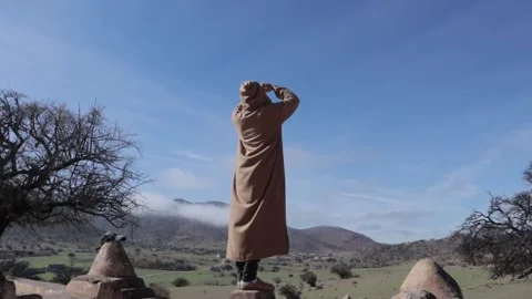 Moroccan Man in Djellaba Overlooking Mountain Landscape 스톡 동영상 332771065