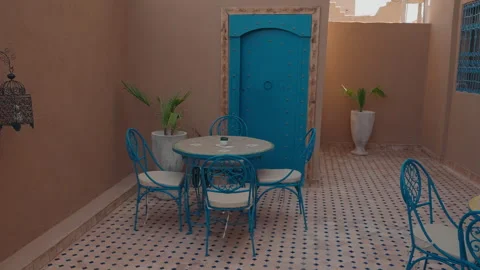 Moroccan riad courtyard with blue chairs round table and zellige tile floor 库存影片 334514716