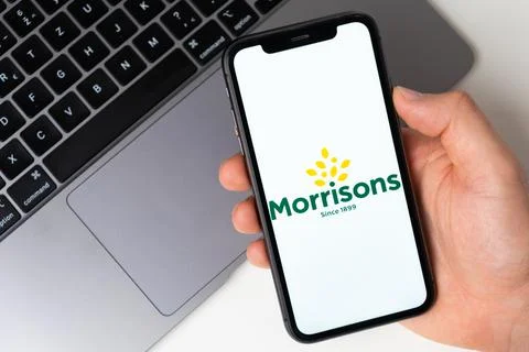 Morrisons the application is open in the smartphone. The man is holding a mobile Foto stock