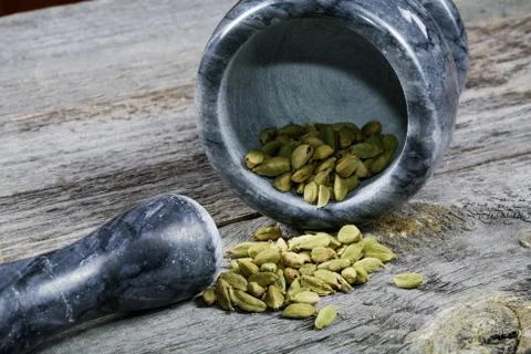 Mortar with cardamom on an old kitchen table Stock Photos