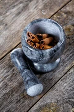 Mortar with cinnamon on an old table Stock Photos