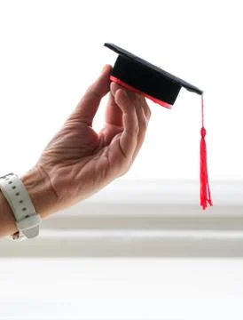 Mortarboard held by hand, isolated in white background Stock Photos