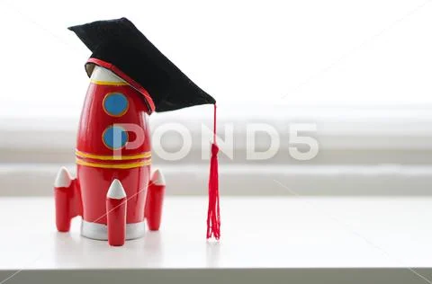 Mortarboard on a toy rocket isolated in white background Stock Photos