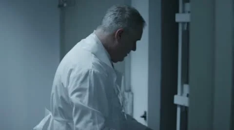 Mortician checking the toe tag on a dead body in the hospital morgue Stock Footage 20453972