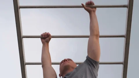 MOSCOW - JULY 28. Athletic guy doing hand ladder crossing on a horizontal bar in Stock Footage 123876941
