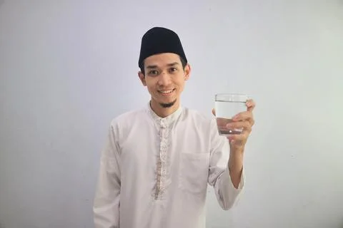 Moslem Asian man smiling at the camera while holding a drinking glass Stock Photos