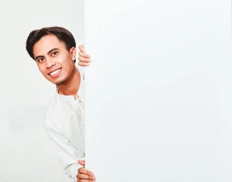 Moslem man peeking behind white billboard showing happy expression Stock Photos