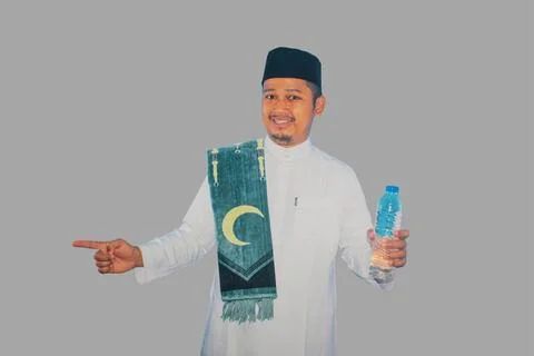 Moslem man smiling while holding a bottle of drinking water and pointing to.. Stock Photos