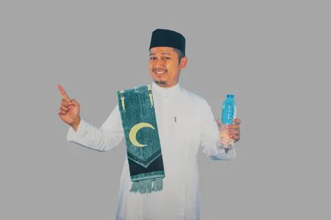 Moslem man smiling while holding a bottle of drinking water and pointing to.. Stock Photos