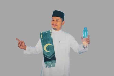 Moslem man smiling while holding a bottle of drinking water and pointing to.. Stock Photos